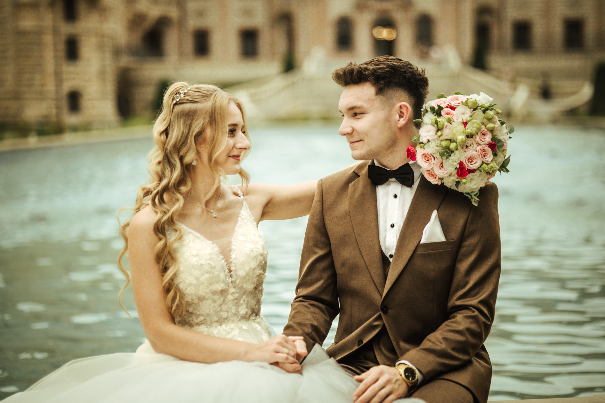 Patrycja i Bartek patrzący się na siebie przy fontannie w ogrodach Zamku Moszna podczas sesji poślubnej